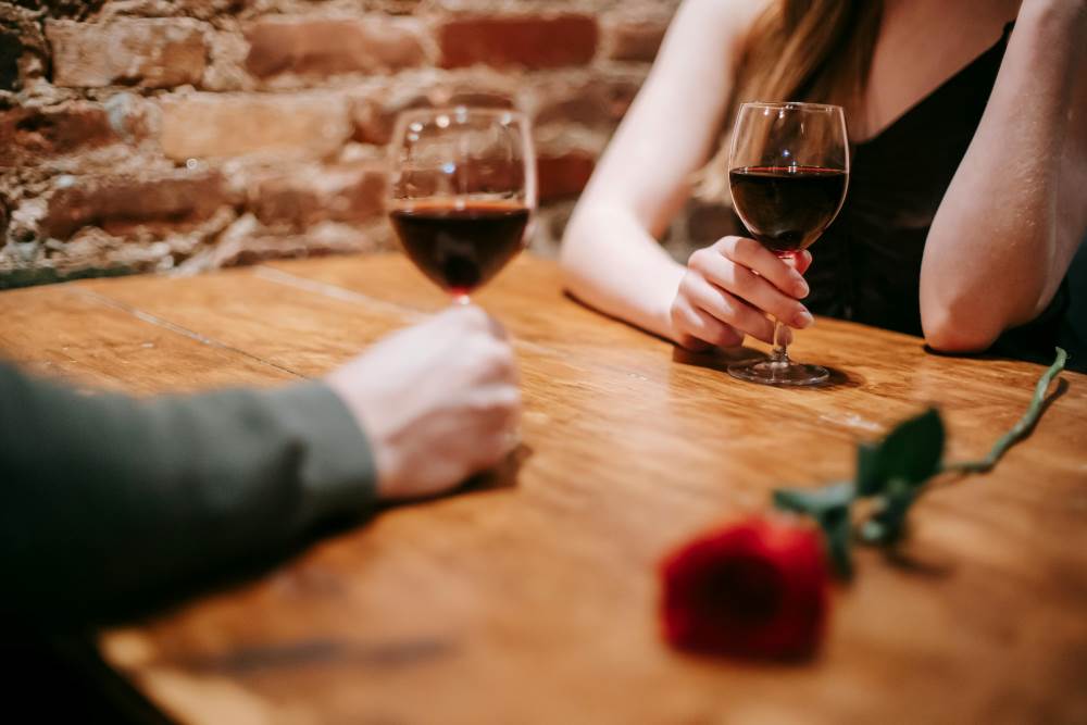 Unrecognizable couple in restaurant on date with wineglasses